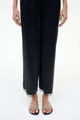 Pearl-beaded black thong sandals worn with cropped dark pants.