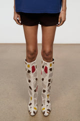Feet shot of tall suede patchwork boots, cream with multicolor heart pattern and block heel