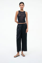 Pearl-beaded black thong sandals on a model with dark wide-leg pants.