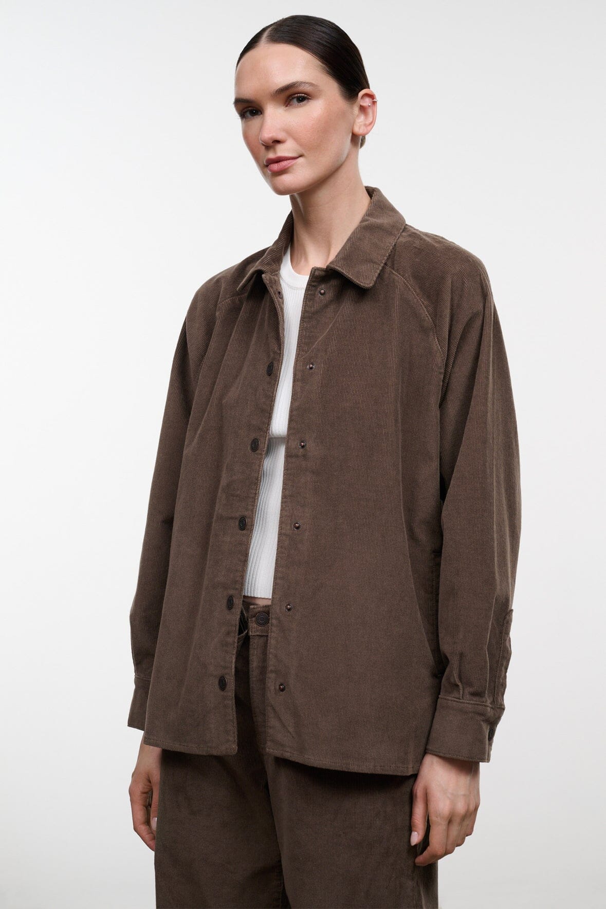 Brown corduroy shirt jacket worn open over a white crewneck