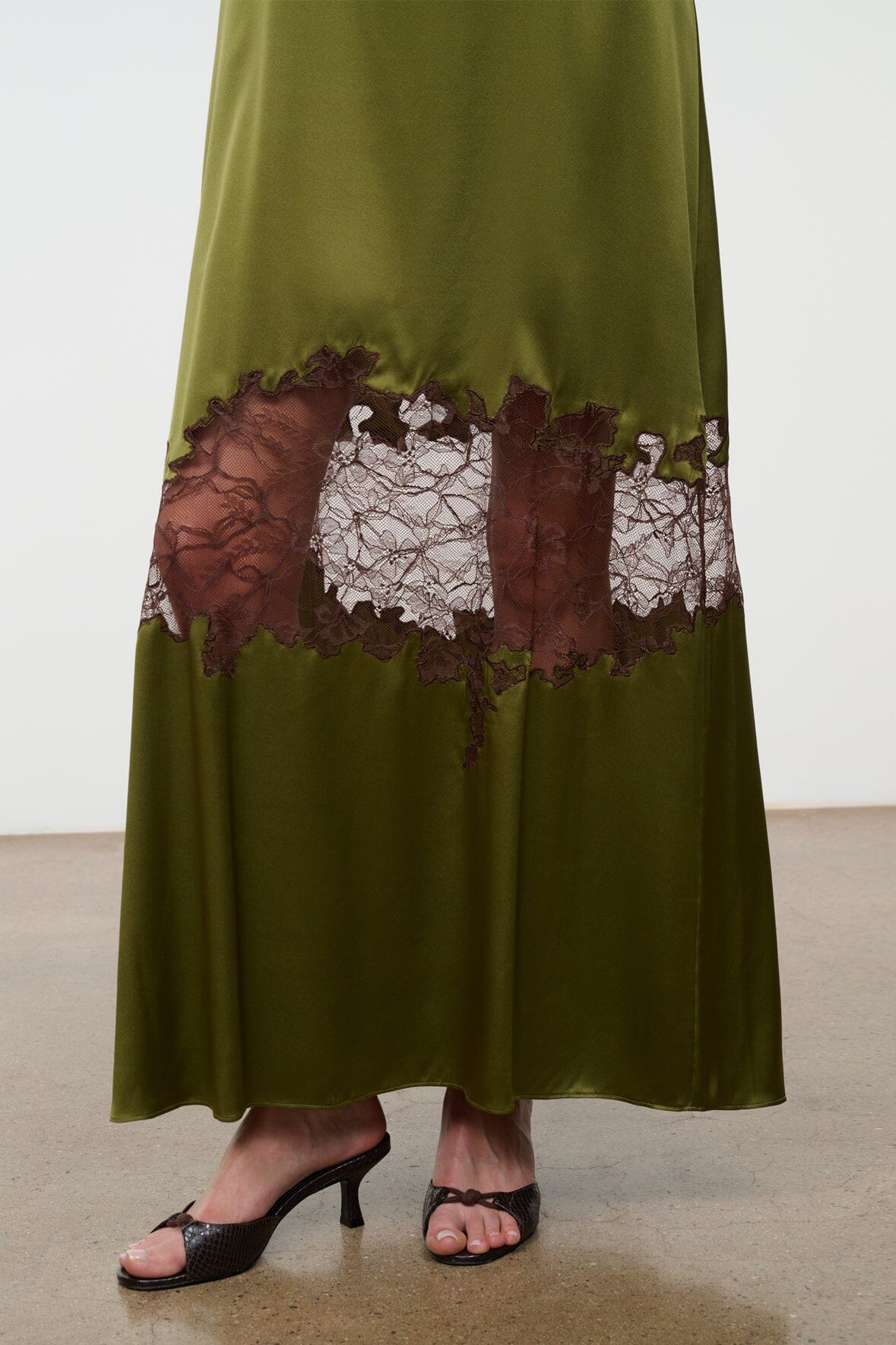 Olive green silk slip dress with brown and white lace panel at the hem