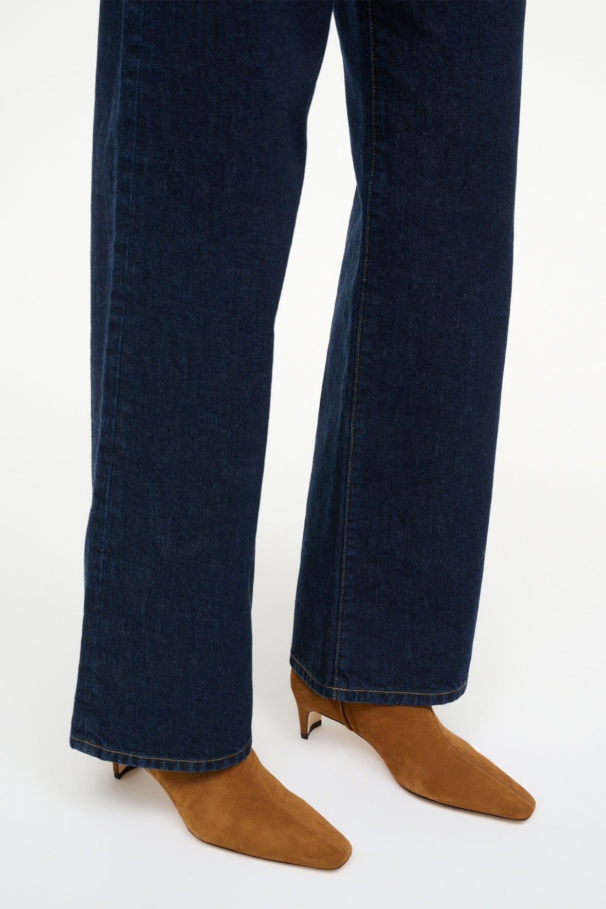 Tan suede ankle boots with pointed toe worn with dark blue jeans