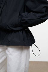 Black hooded wind jacket with cinched waist and drawstring hem