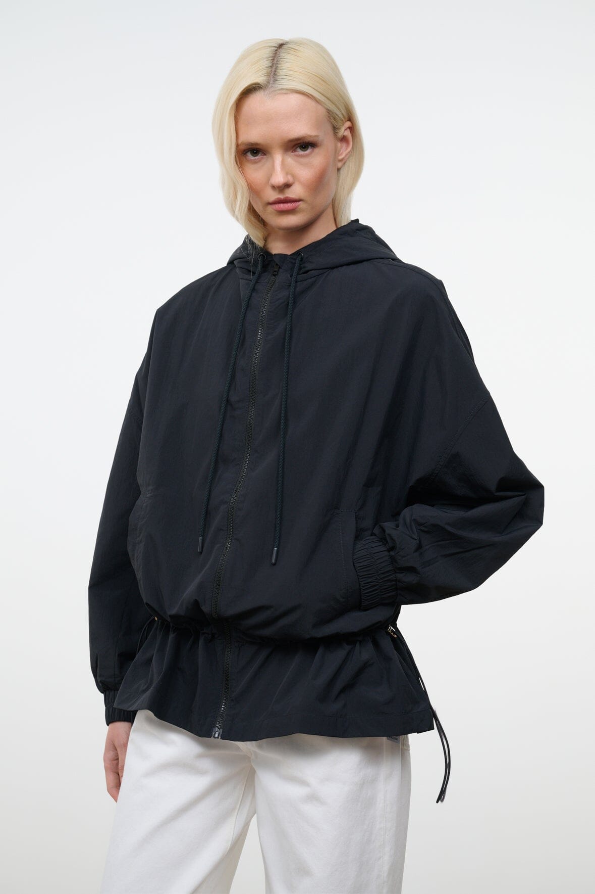 Black hooded wind jacket with full sleeves, cinched waist, drawstring hem