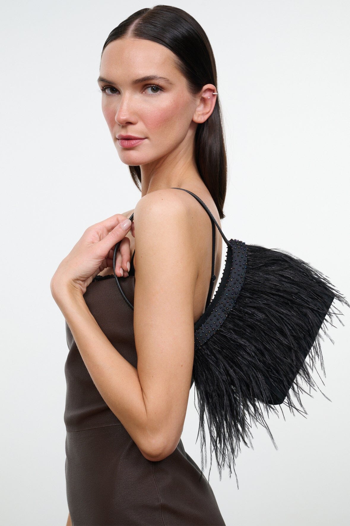 Black mini handbag with long fringe trim and thin shoulder strap.