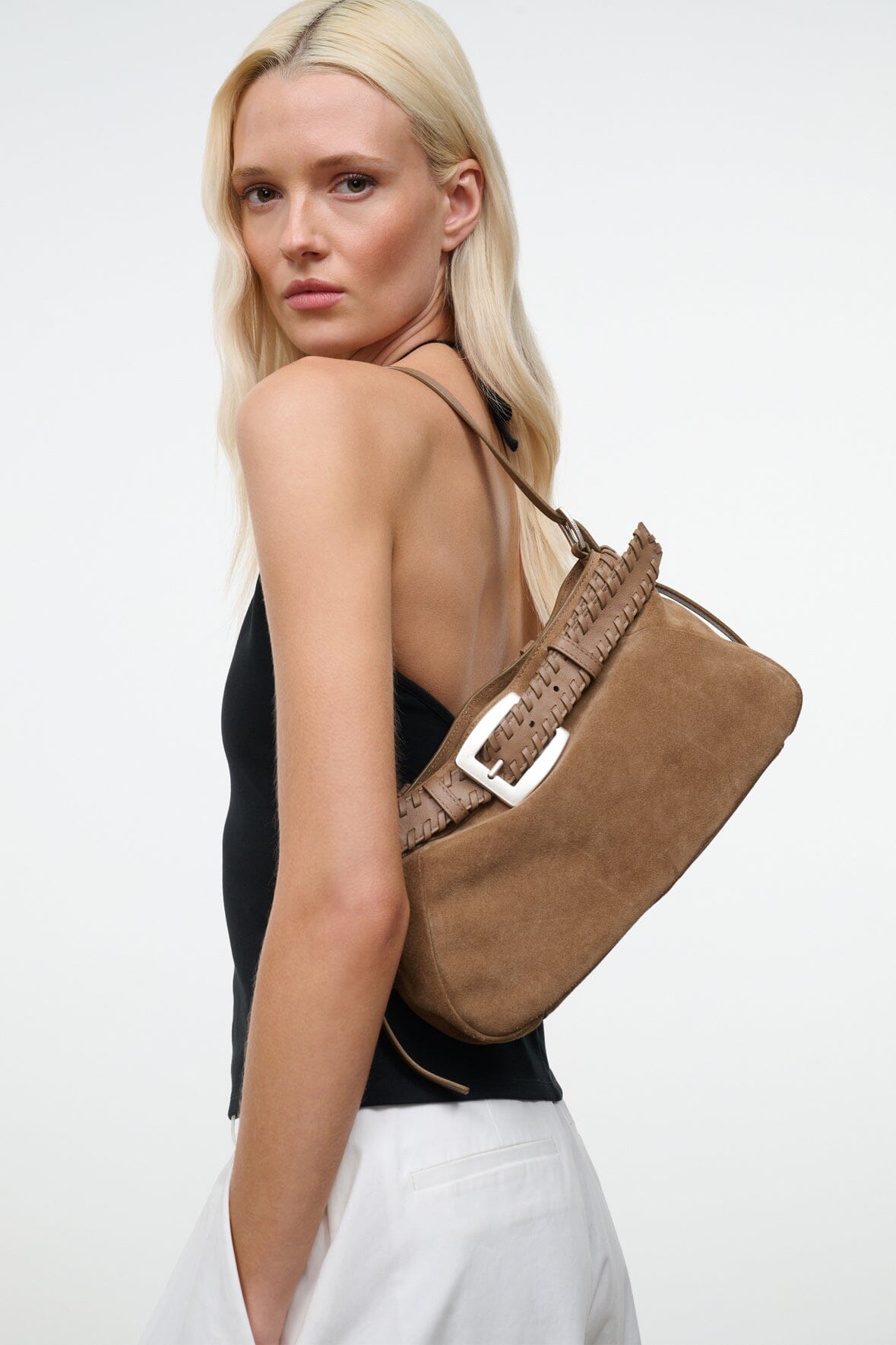 Tan suede shoulder bag with woven strap band and silver buckle, side view