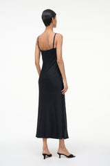 Black suede mule worn with a black midi dress, heel and toe visible