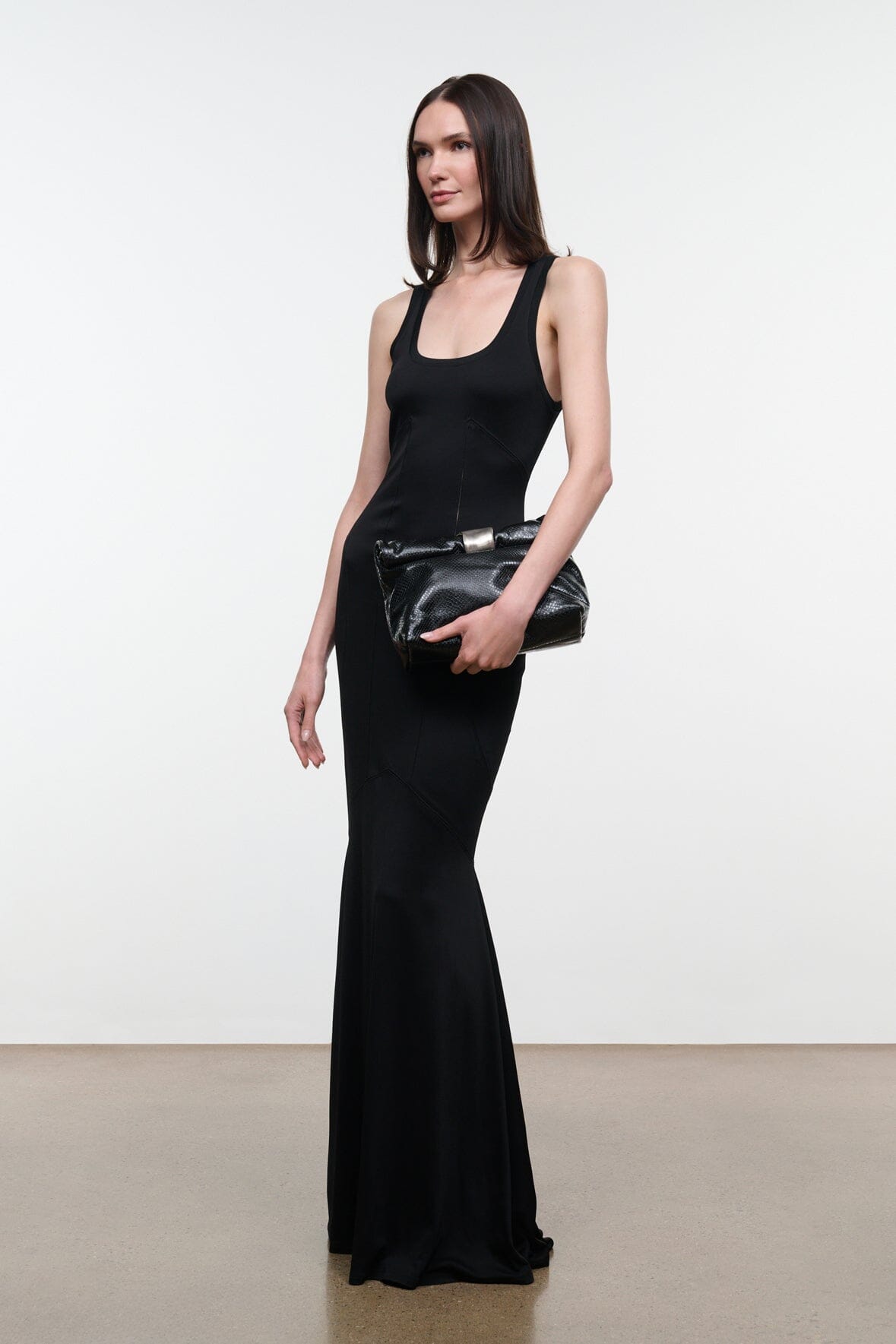 Black snake-textured cuff clutch with silver bar closure, held low at front