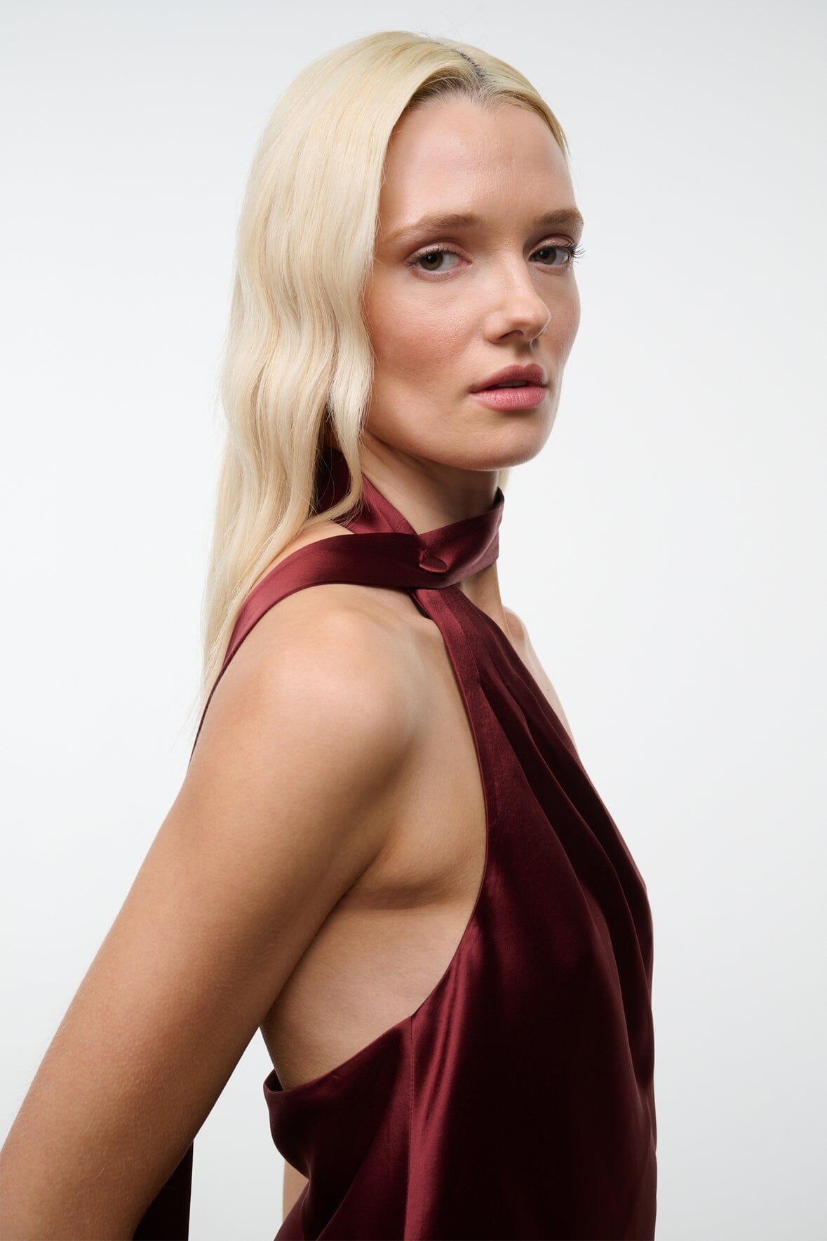 Wine satin halter dress with halter strap and open-back drape detail, sleeveless.