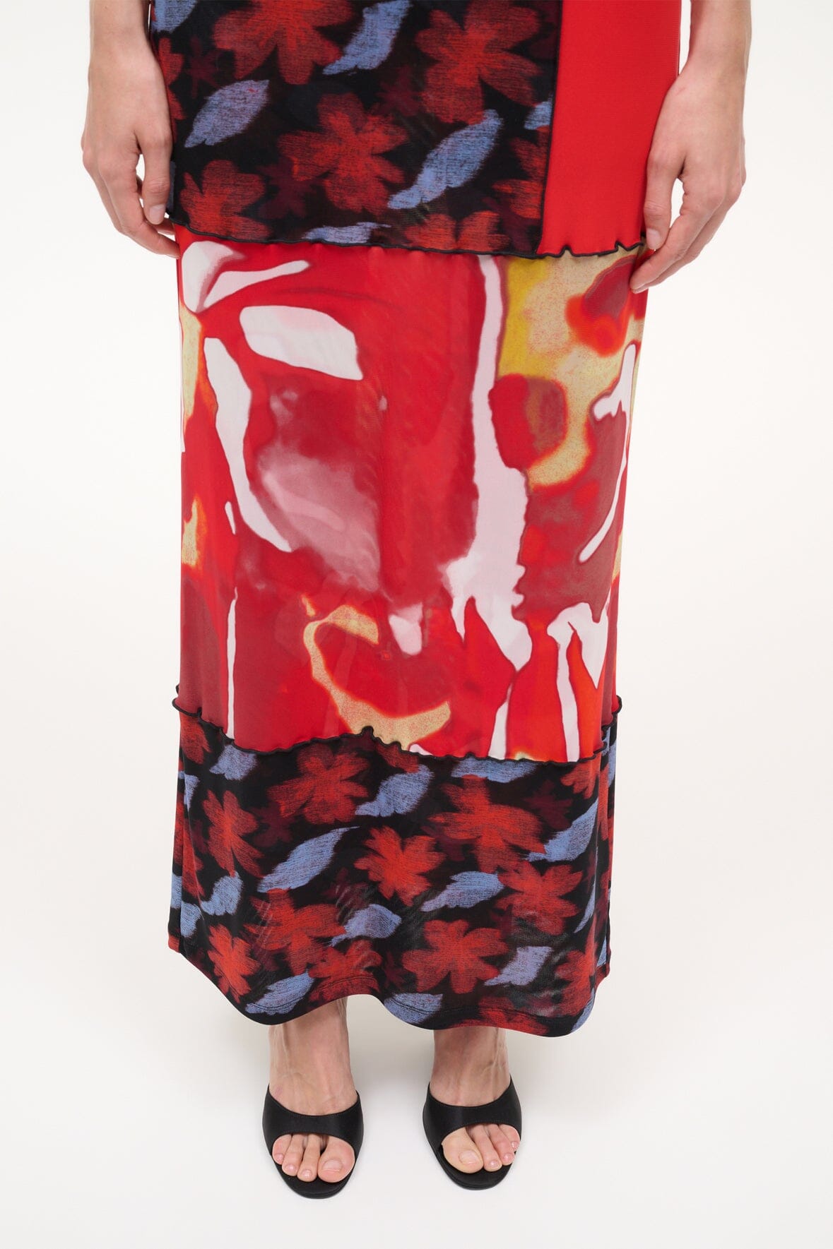 Black high-wedge slide sandals worn with a red and black floral skirt