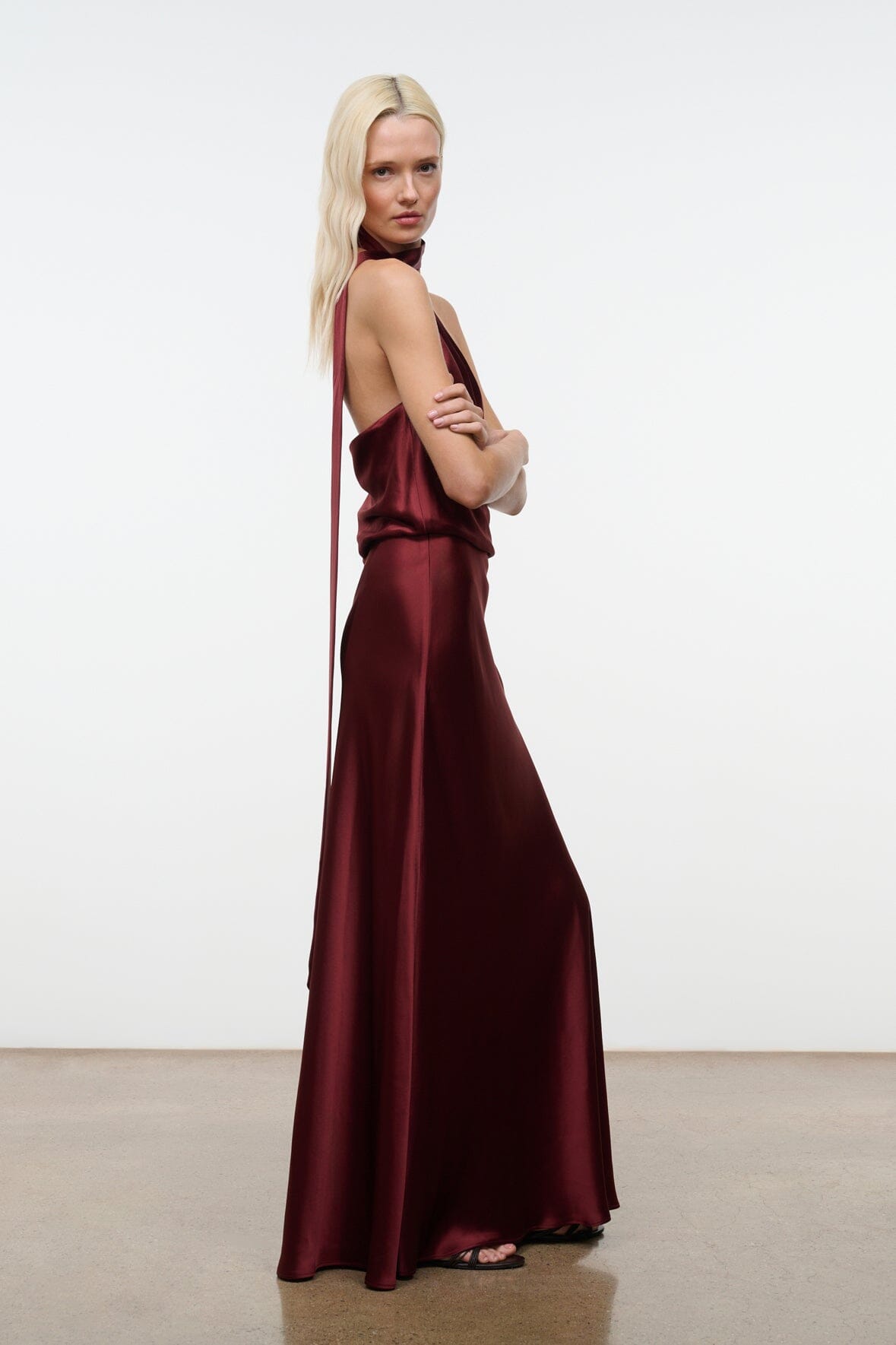 Wine satin halter maxi dress with diagonal halter strap and flowing skirt.