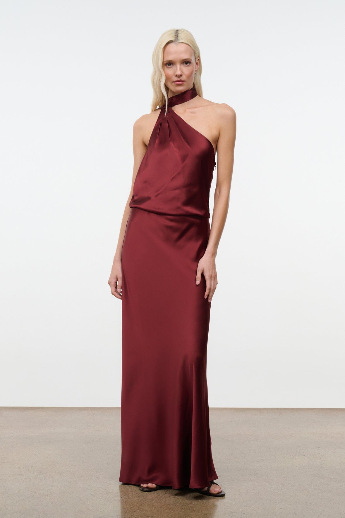 Wine satin halter maxi dress with asymmetric halter neckline and fitted waist.