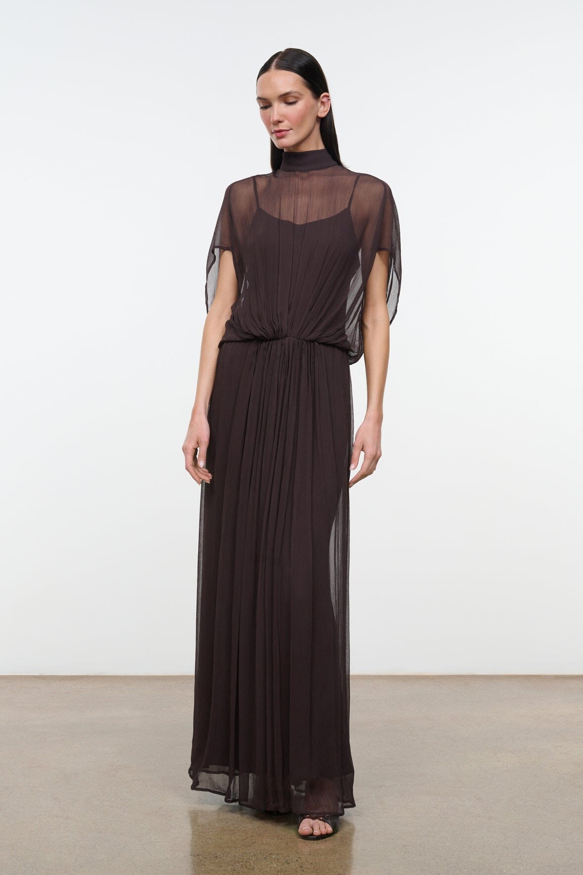 Dark brown high-neck sheer maxi dress with elastic waist and flowing pleated skirt