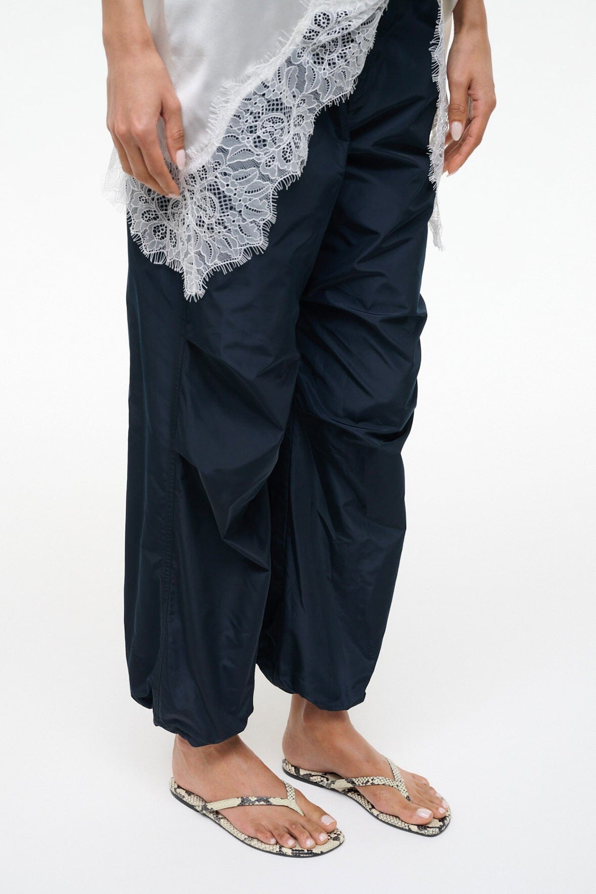 Snake-print thong sandals worn with navy drawstring pants and lace-trim top