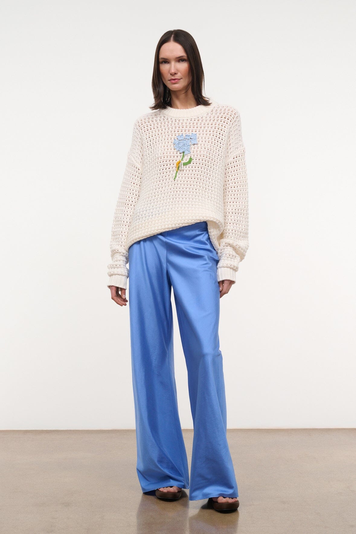 Cream knit crewneck sweater with long sleeves and centered blue flower motif