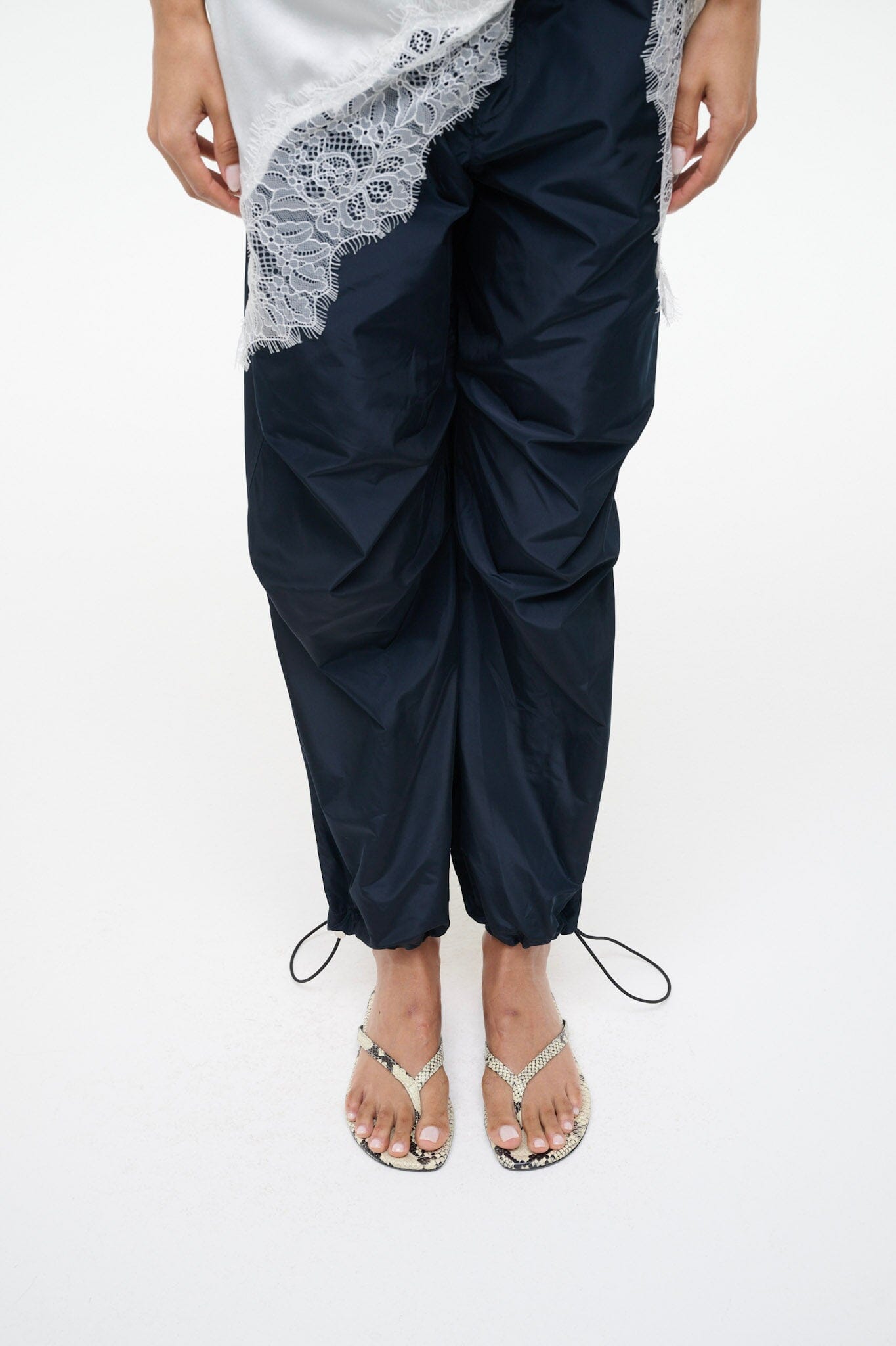 Snake-print thong sandals worn with navy drawstring pants and lace trim