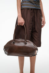 Distressed brown shoulder bag with top zipper and side strap loops, front view