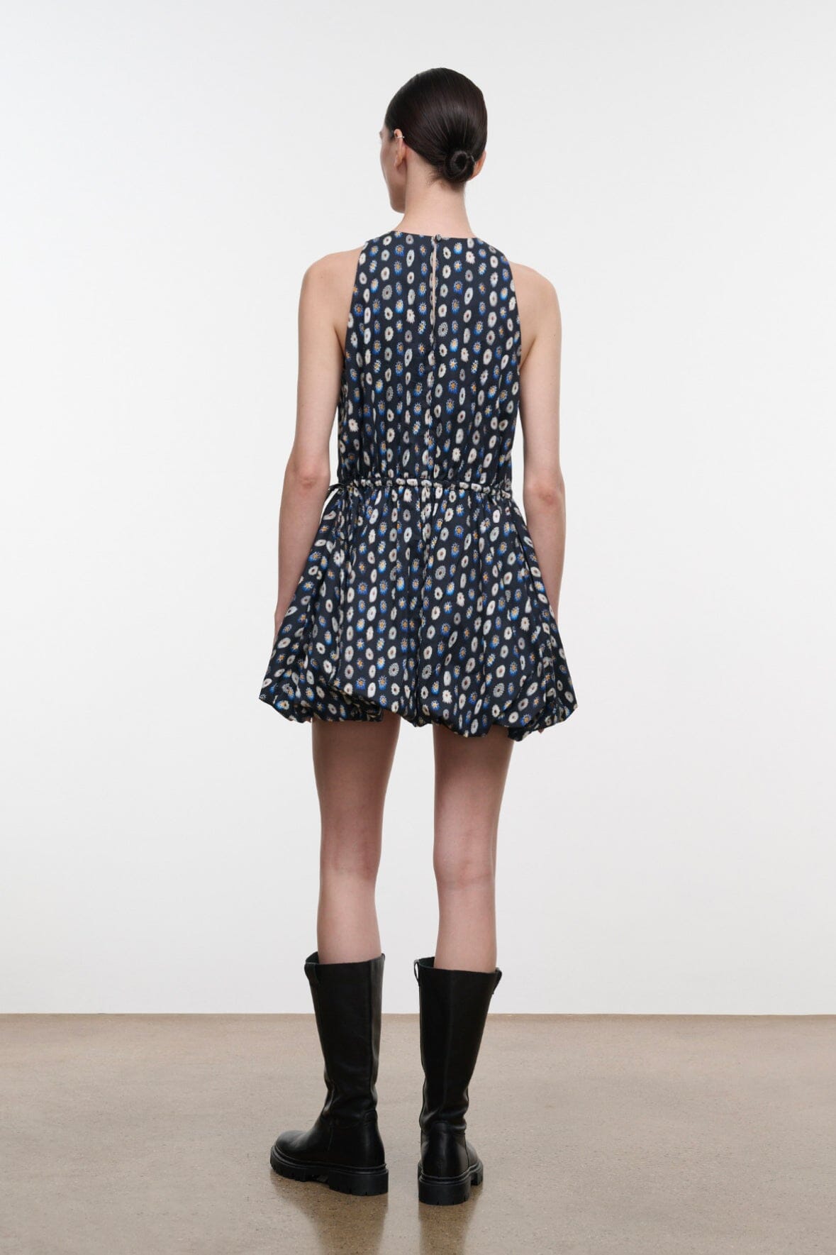 Back view: navy sleeveless mini dress with teardrop print and flared pleated skirt