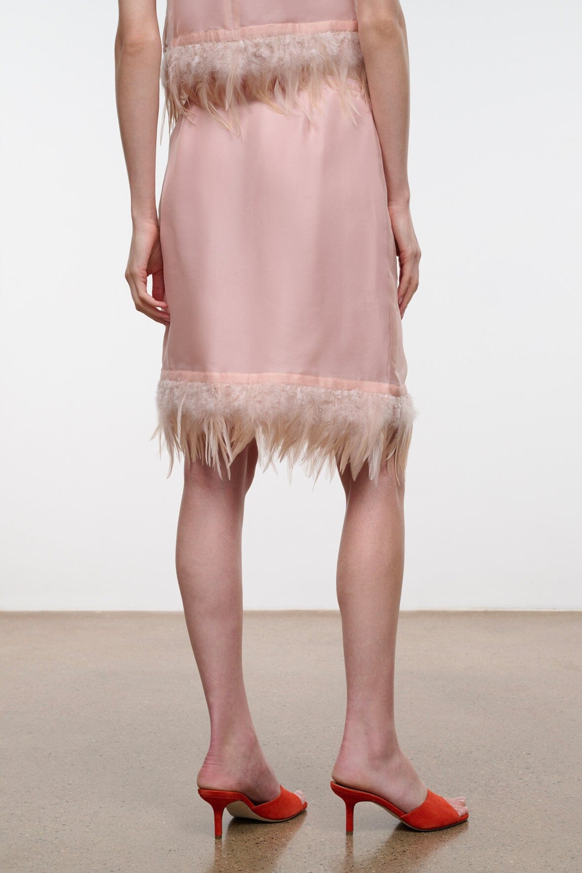 Light pink satin skirt with feather fringe hem, sleeveless top pairing visible