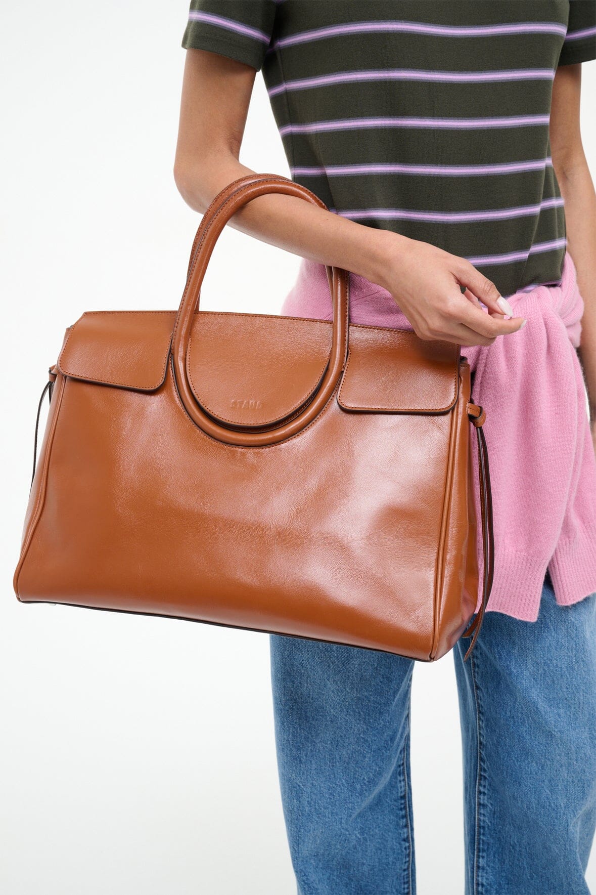 Brown carryall handbag with curved ring front detail and gold hardware accents