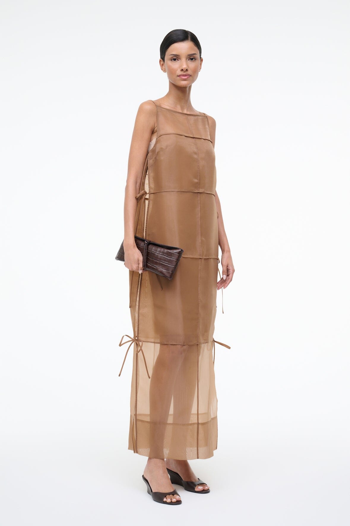Brown croc-textured leather clutch, held at side with adjustable strap