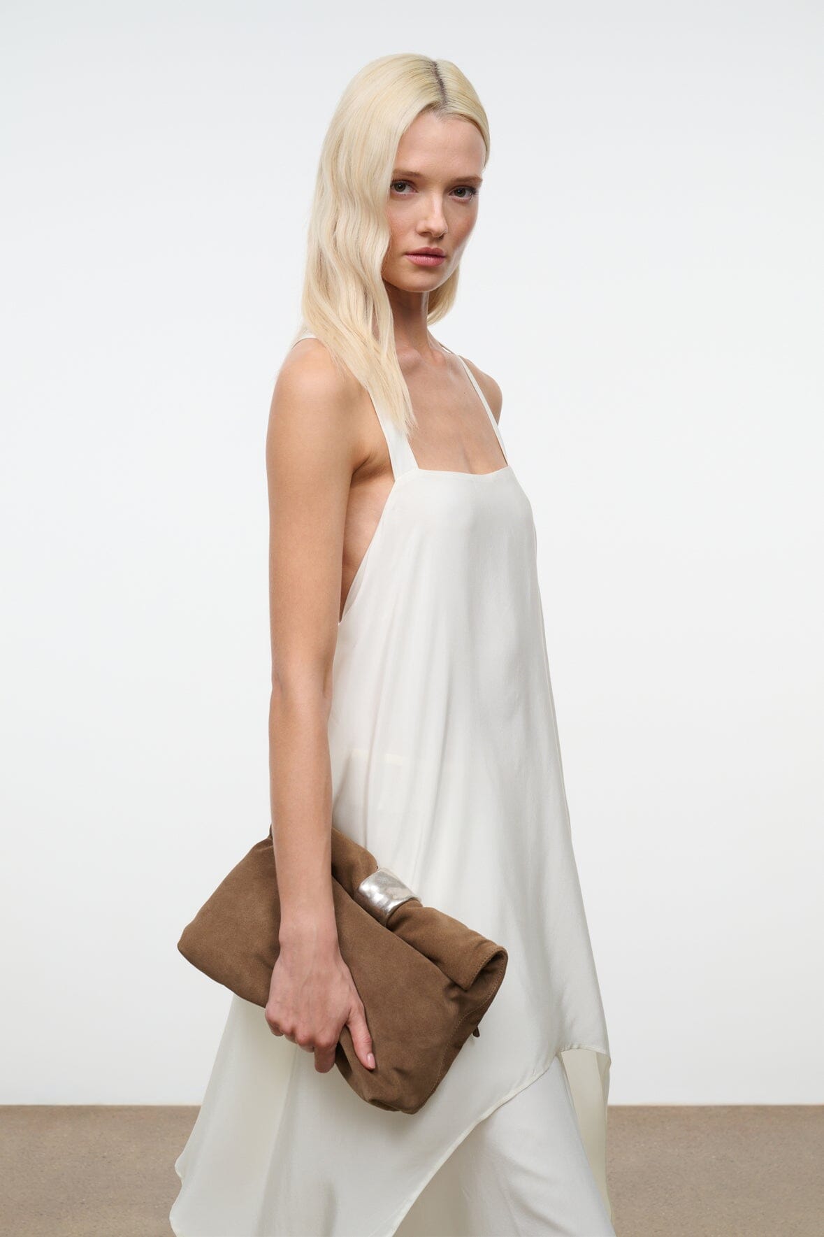 Husk brown cuff clutch with silver snap hardware in model’s hand