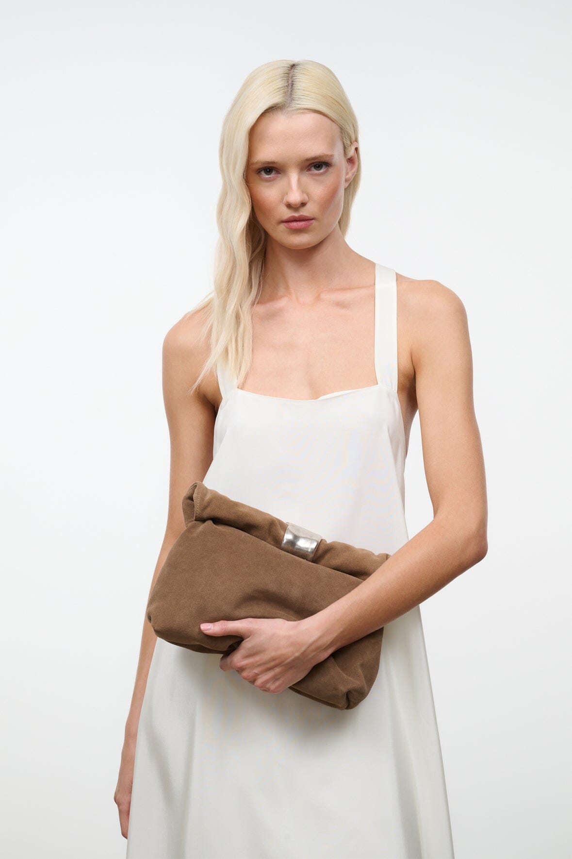 Husk brown cuff clutch with silver snap top held across model’s waist