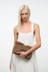 Husk brown cuff clutch with silver snap top held across model’s waist