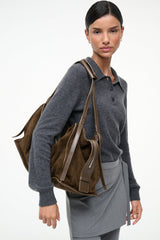 Truffle suede shoulder bag worn with top handles and side tassel details