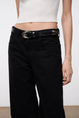 Black croc-texture belt with silver oval buckle on dark jeans.