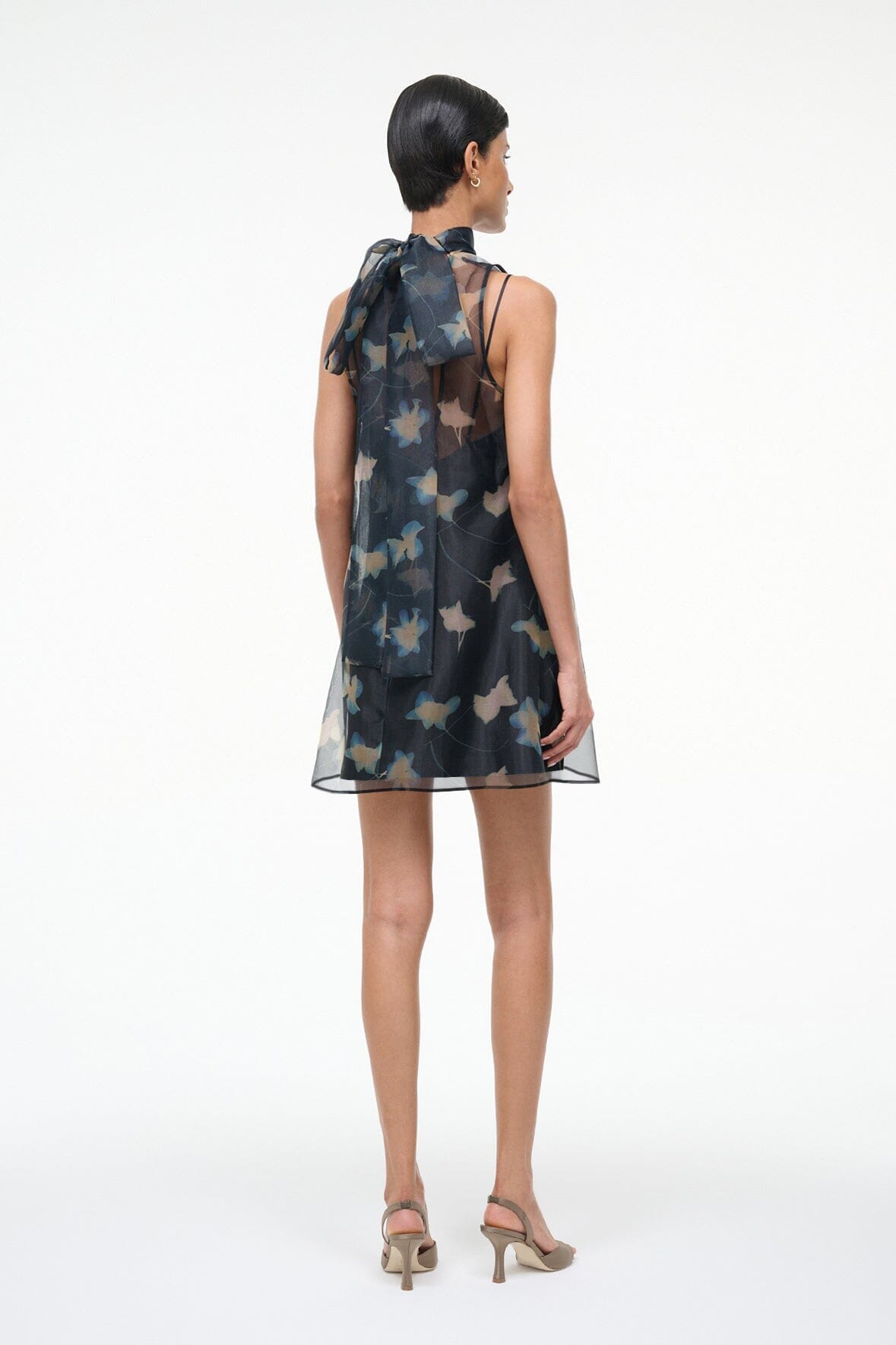 Back view of black sleeveless mini dress with high neck and bird print over sheer mesh