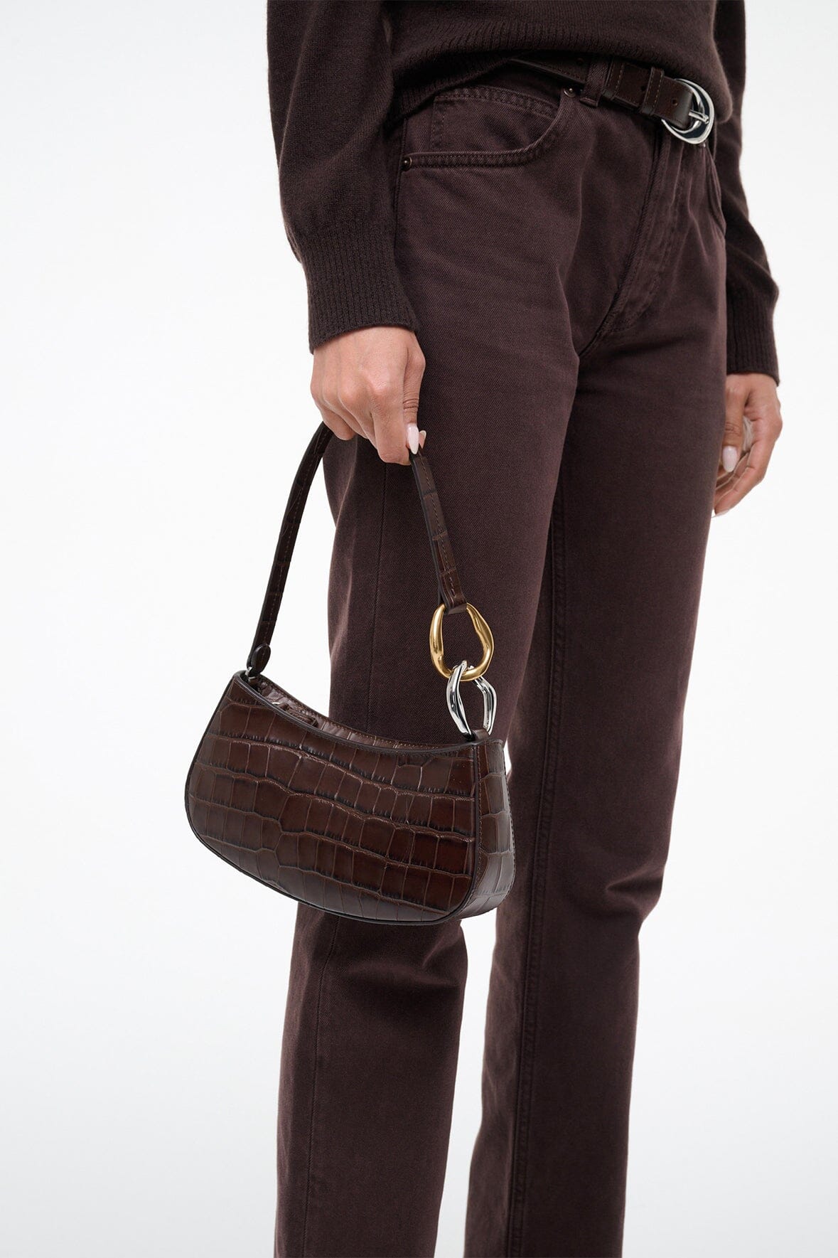 Brown croc-texture handbag with gold rings, carried by short strap