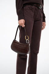 Brown croc-texture handbag with gold rings, carried by short strap
