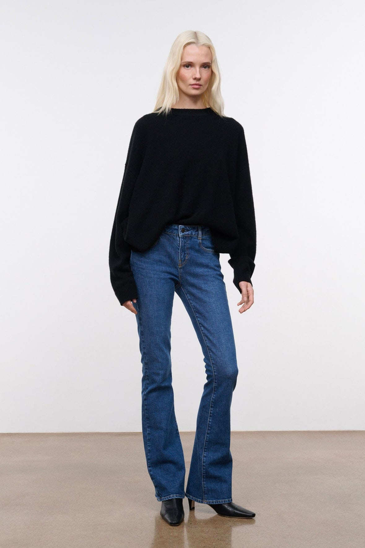 Stone blue denim flare jeans on model, mid-rise with wide-leg straight fit