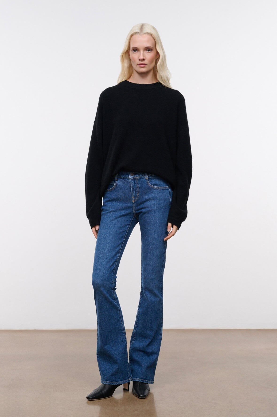 Stone blue denim flare jeans on model, mid-rise with straight wide-leg shape