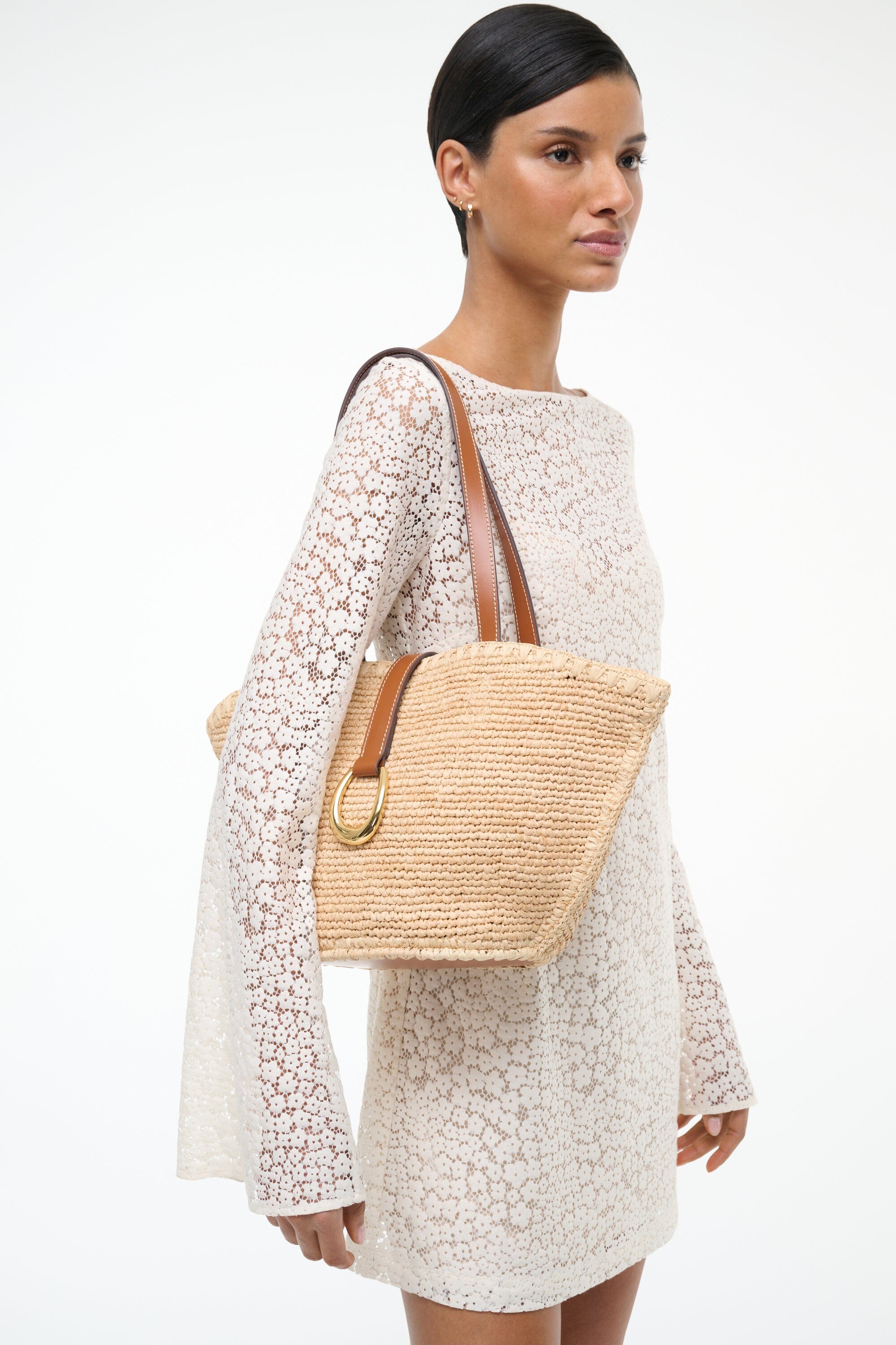 Natural tan woven tote bag side view with tan leather handles and front pocket tab