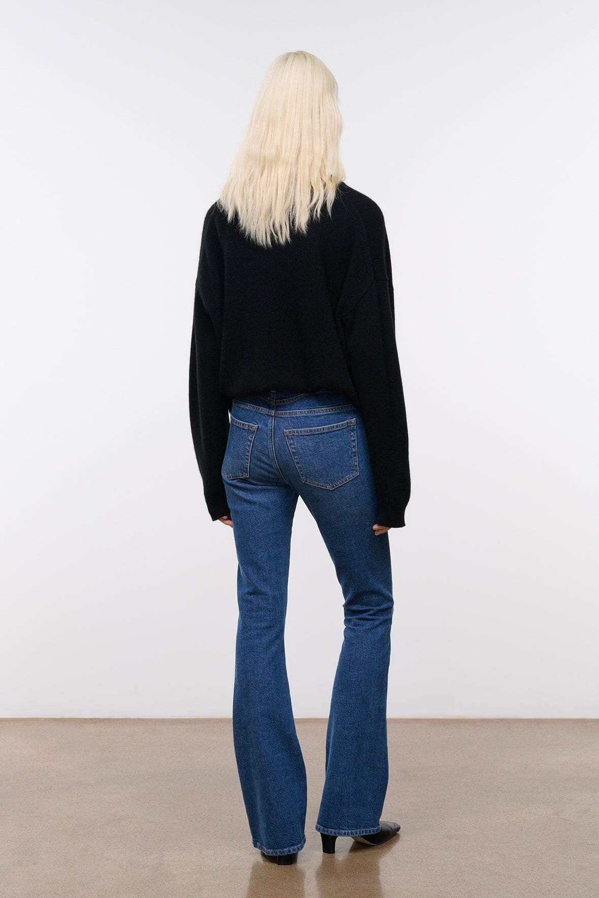 Stone blue denim flare jeans on model, back view with cuffed wide-leg hem
