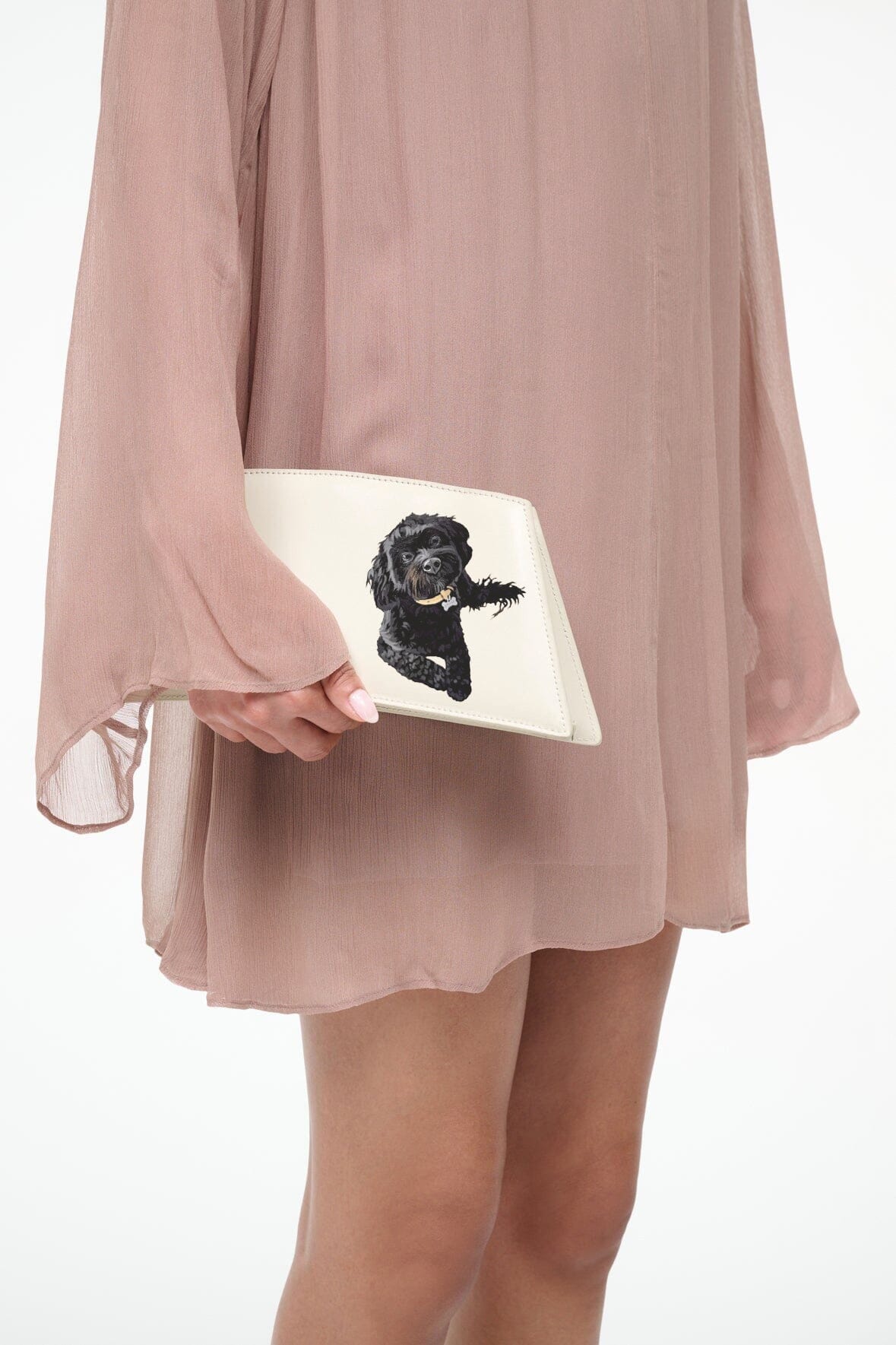 Cream shoulder bag held in hand with black dog portrait front