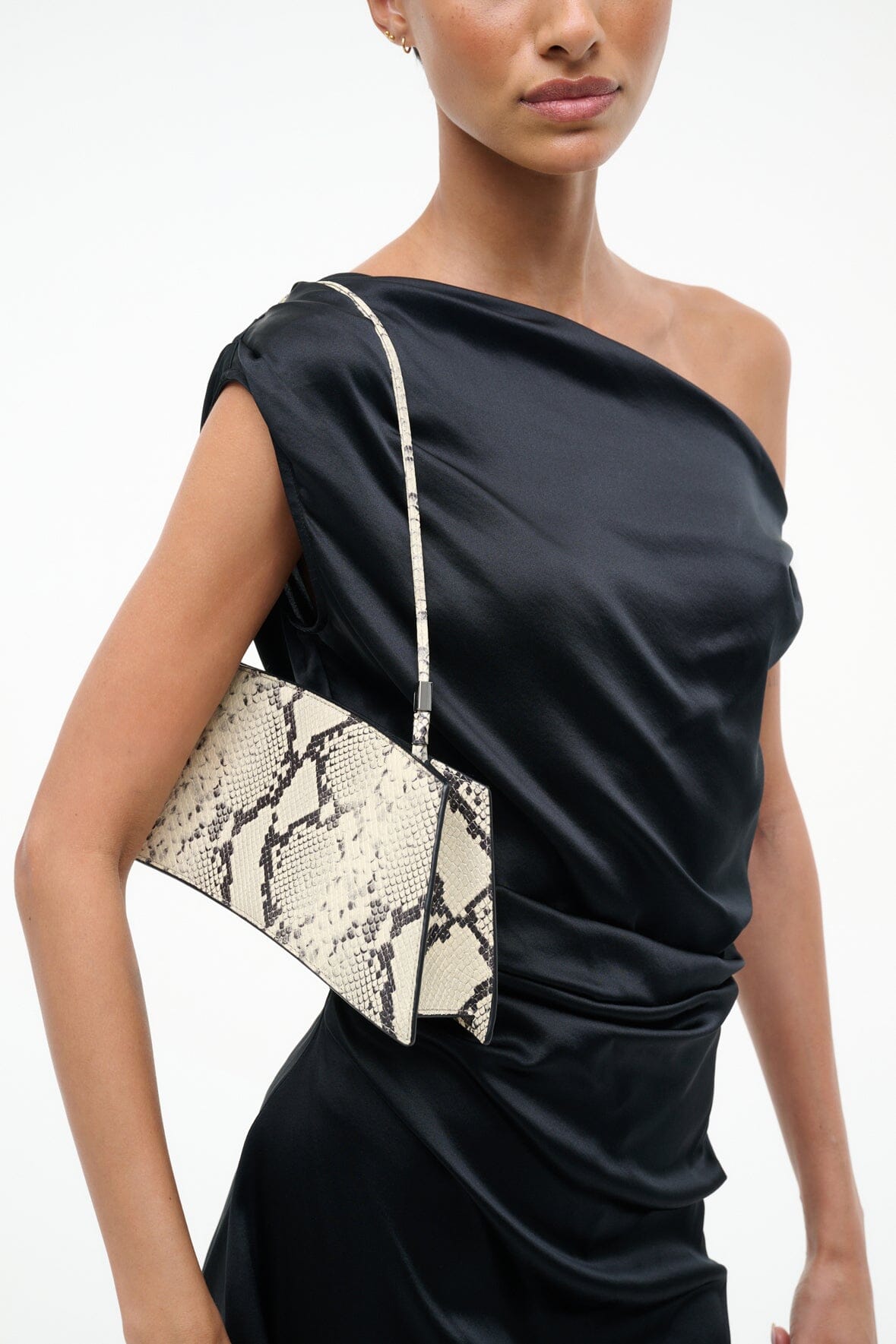 White snake-pattern shoulder bag front with wide diagonal strap over dress