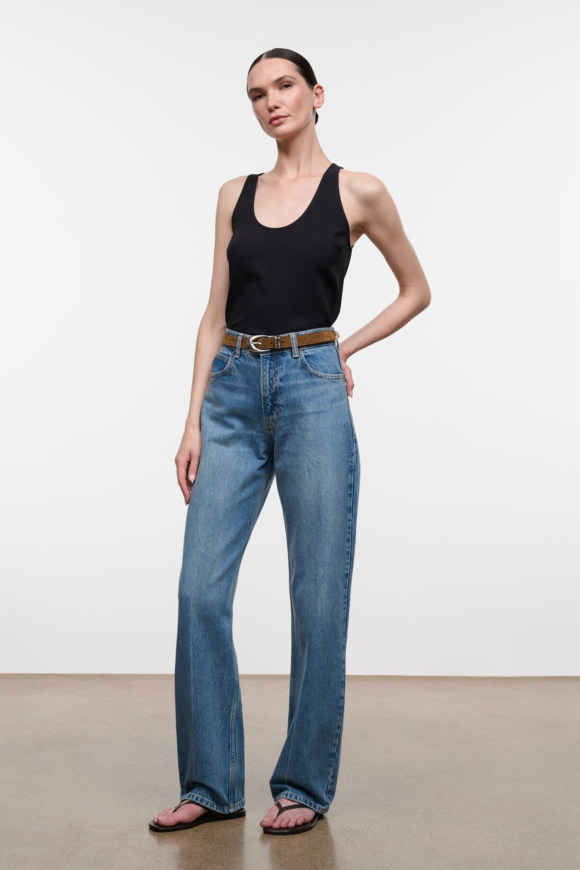 Brown suede belt with silver buckle on blue jeans, styled at the waist.