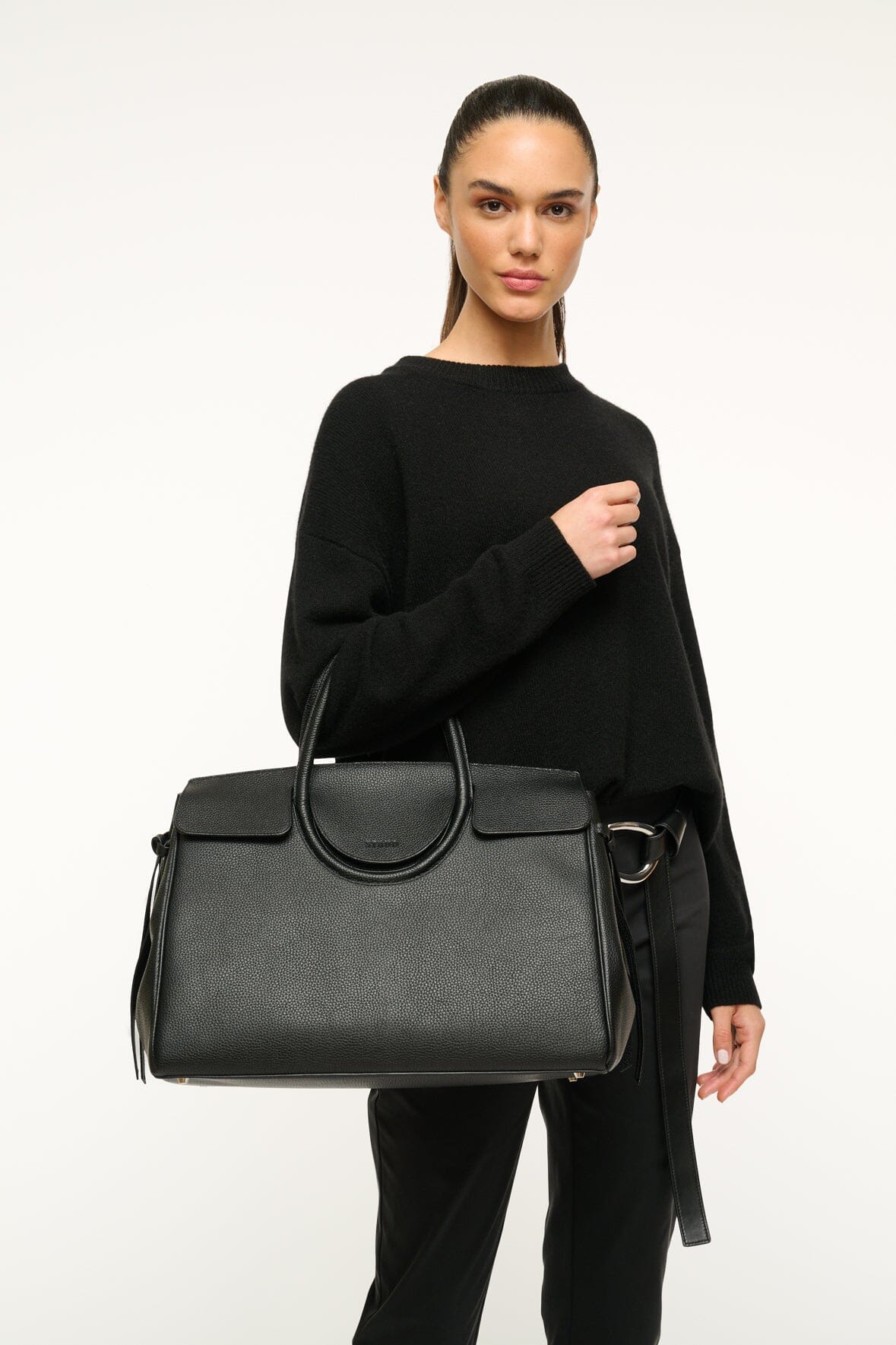 Maude carryall bag in black with top handles and front metal ring detail.
