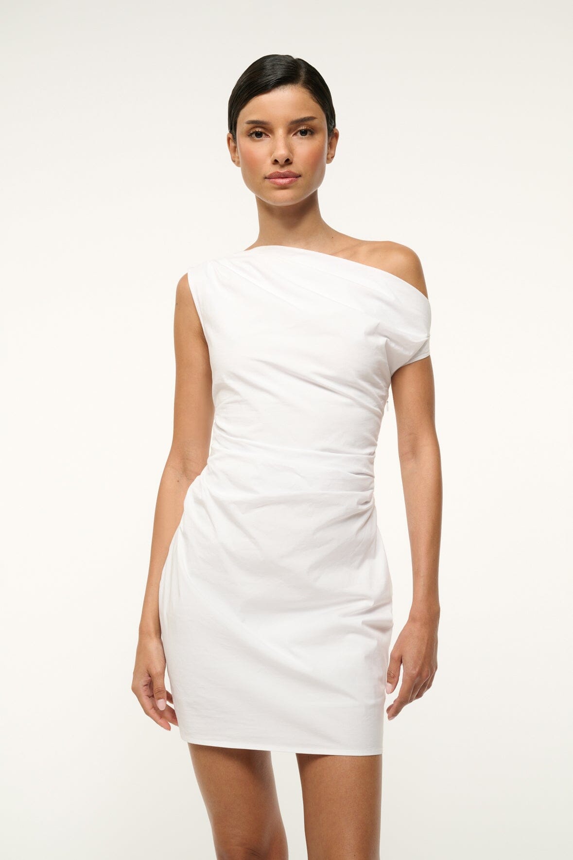 White mini dress with asymmetrical off-shoulder neckline, fitted waist