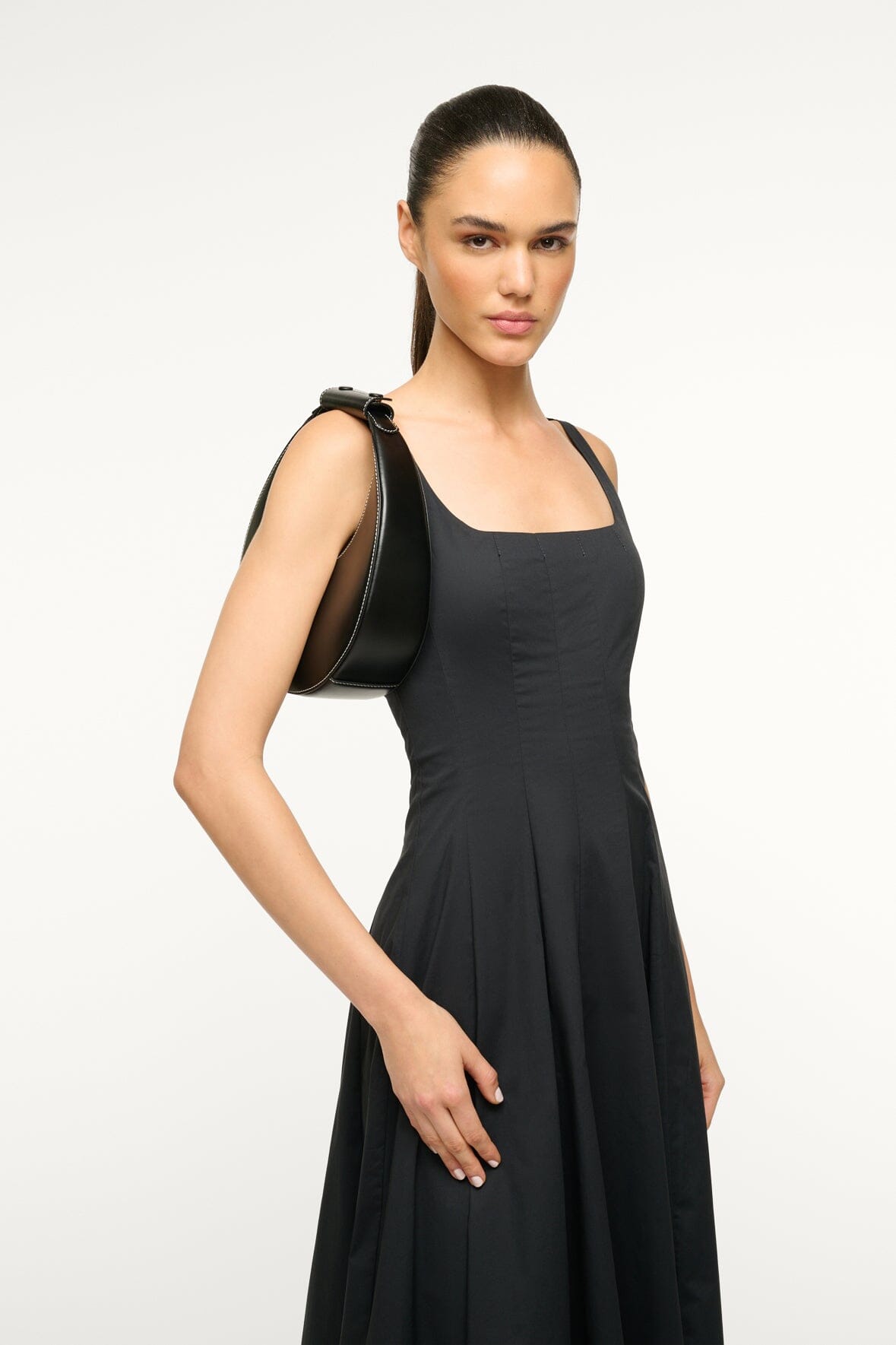 Black mini moon bag worn over shoulder with a black dress