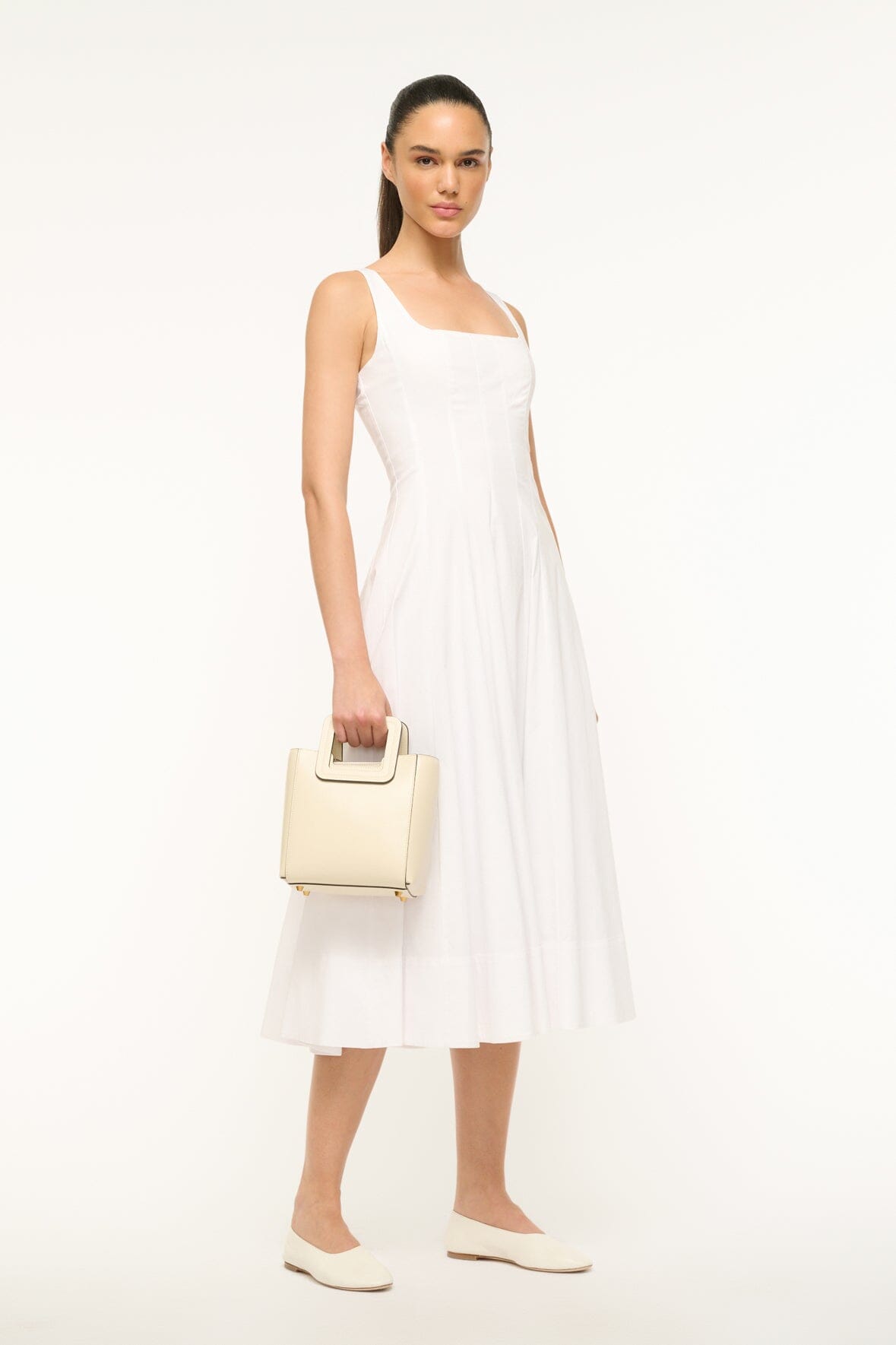 Model carrying mini cream leather bag with top handle and small front pouch
