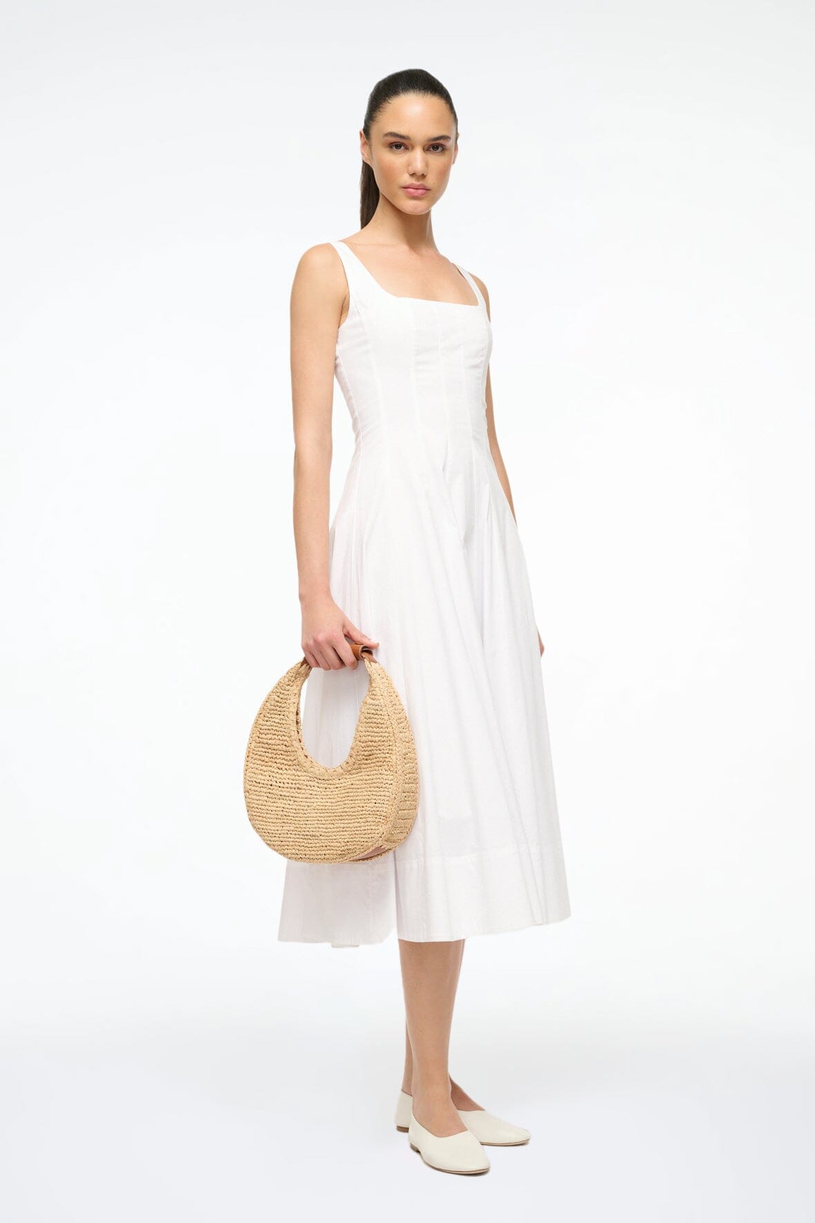 Natural raffia moon bag with brown leather top handle, carried over shoulder