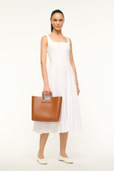 Tan leather bag held in hand with top handle and compact pouch shape