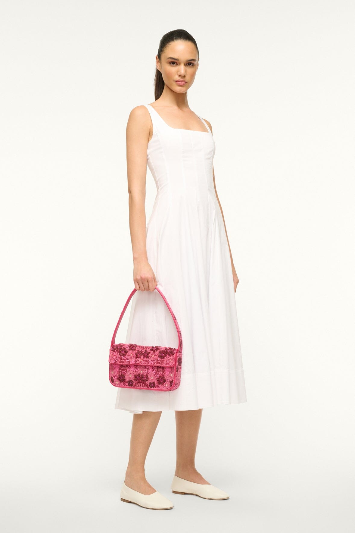 Pink beaded crossbody bag with short top handle and textured floral bead pattern.