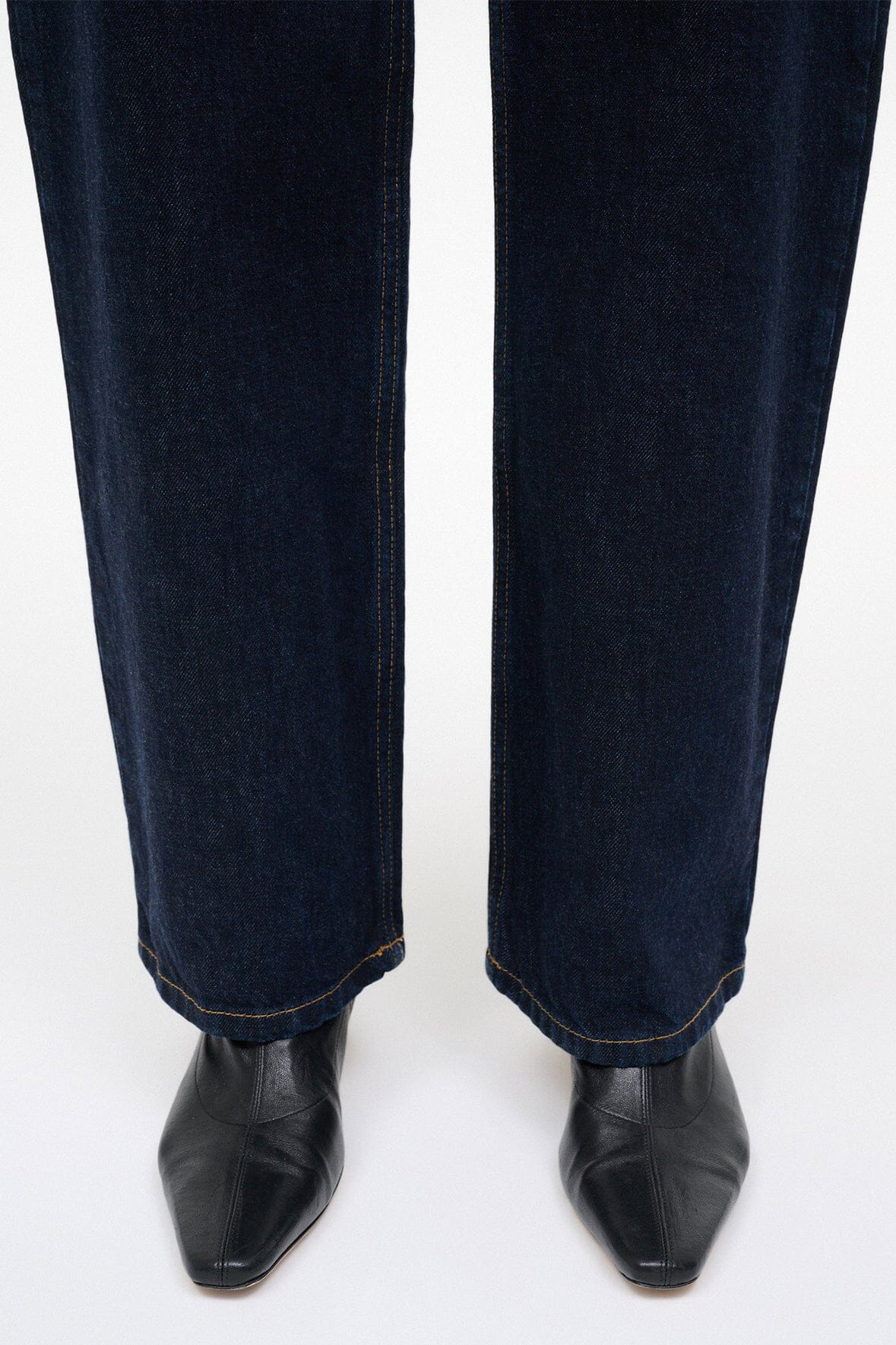 Pair of black ankle sock boots worn with dark denim jeans.