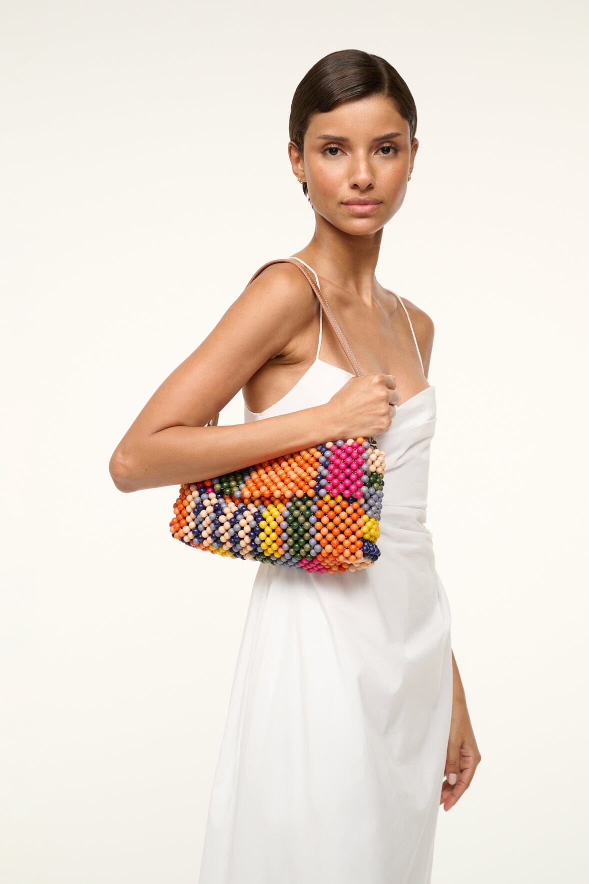 TIMMY shoulder bag with multicolor beaded stripes worn across chest with a white dress.