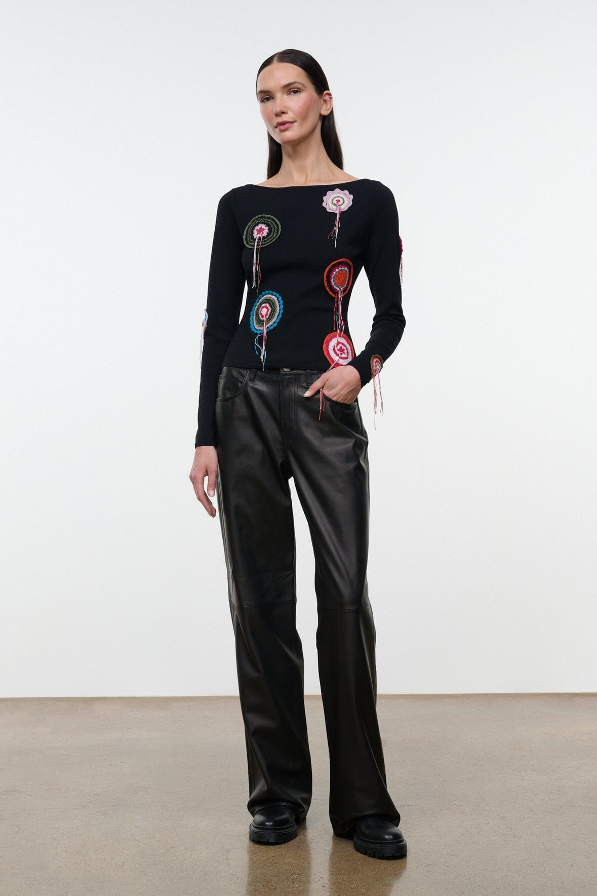 Black long-sleeve top with circular embroidered patches and tassel fringe
